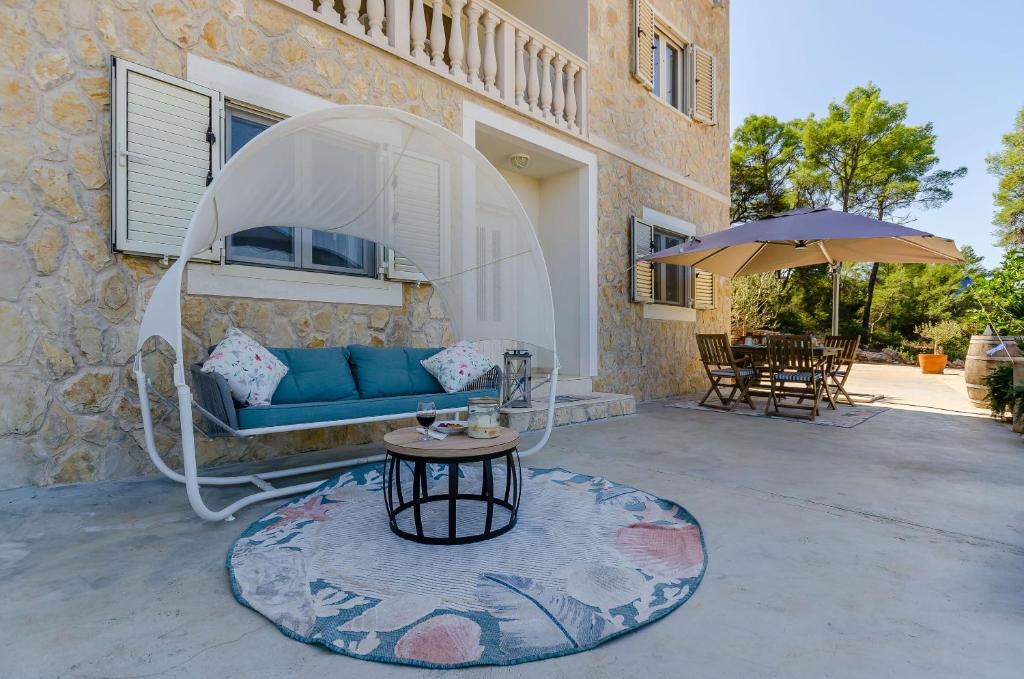 a patio with a blue couch and an umbrella at Apartments Vila Jelka in Vrboska