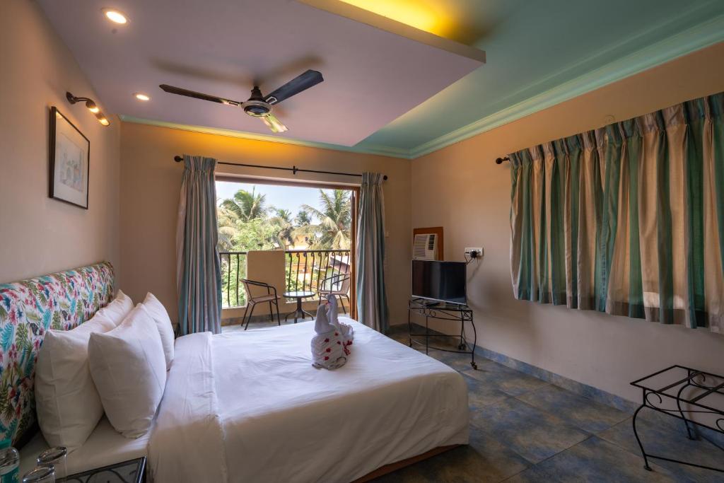 a bedroom with a bed and a balcony at Victor Exotica An Indy Resort in Candolim