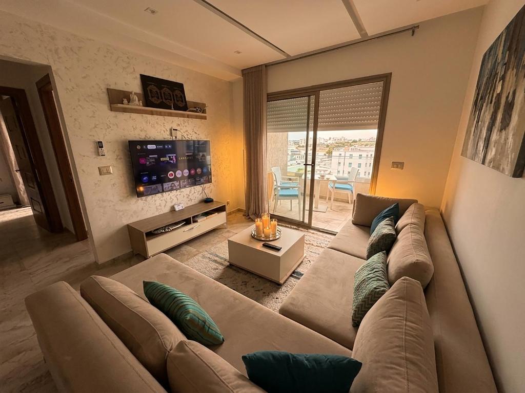 a living room with a large couch and a tv at Appt lux Hammamet Nabeul in Hammamet Nord