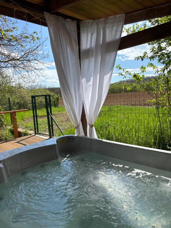 a hot tub in the backyard with a view of a field at Pillanat Wellness Kabin in Bánk