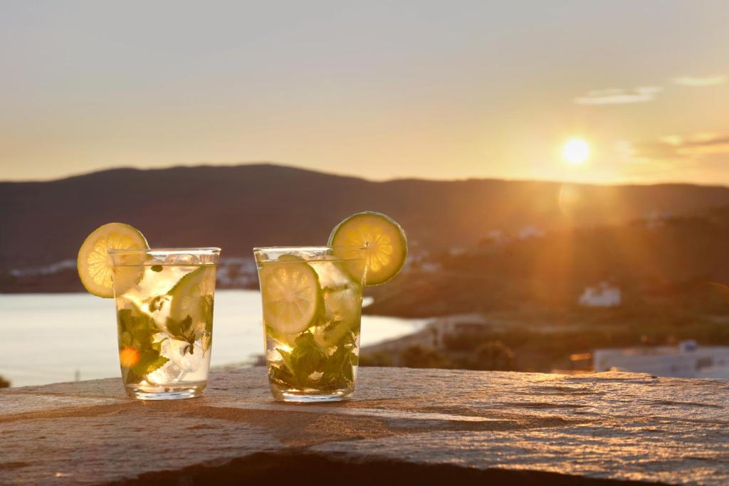 two glasses of lemonade sitting on a table with the sunset at Aithra -Agios Petros Andros in Gavrio