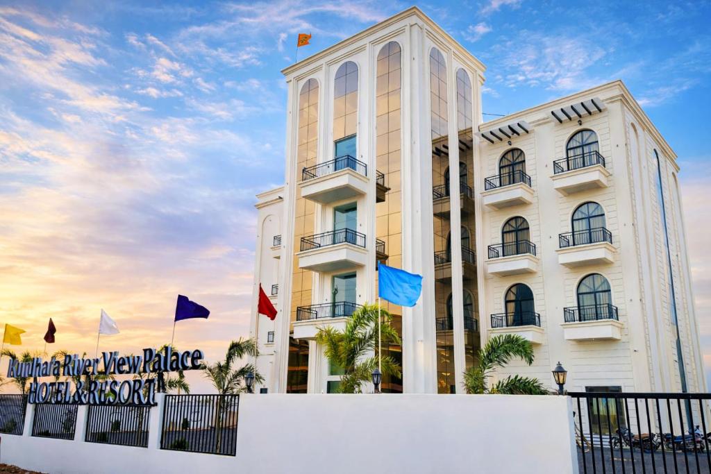 a white building with flags in front of it at Mandhata Riverview Palace in Mortakka