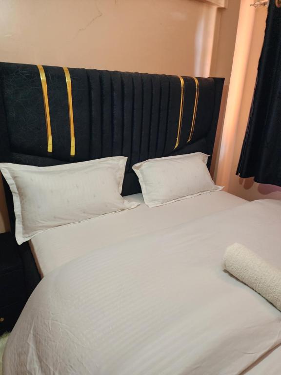 a bed with white pillows and a black and yellow headboard at Pure excellence homes in Ruiru