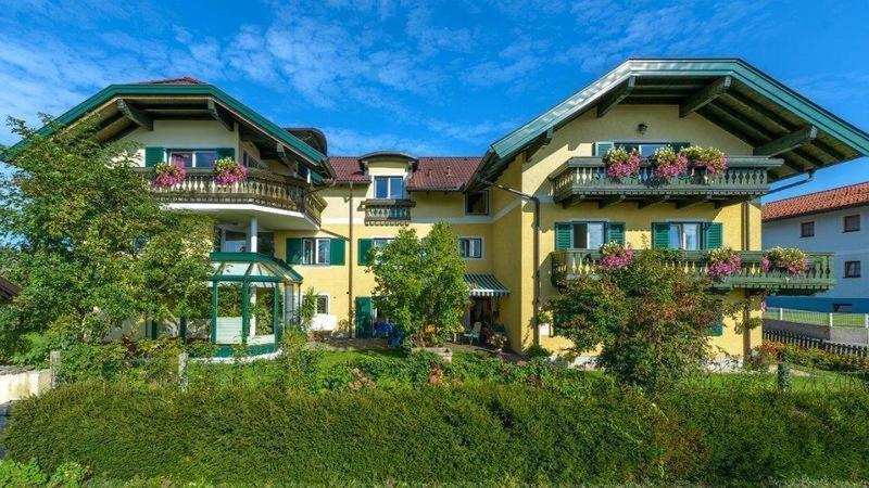 a large yellow house with flowers on the balconies at SPITZAUERs APARTMENTs in Anthering