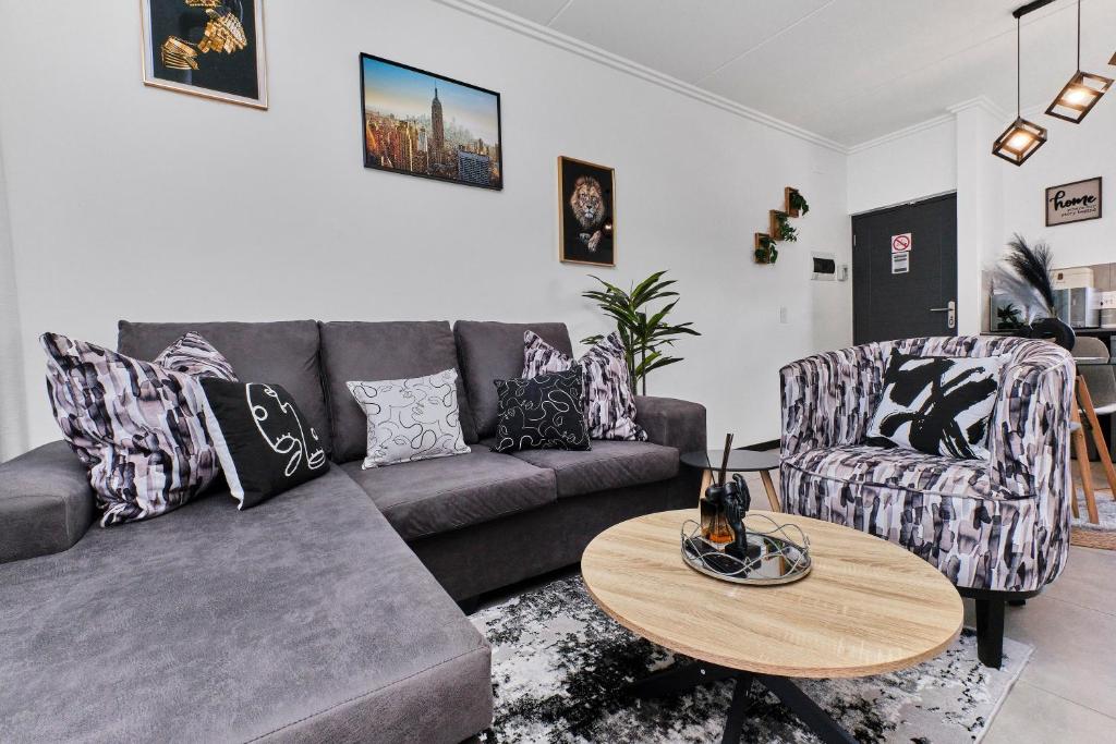 a living room with a couch and a table at Chanty Serenity- workstation, gym, backup power &Pool in Sandton