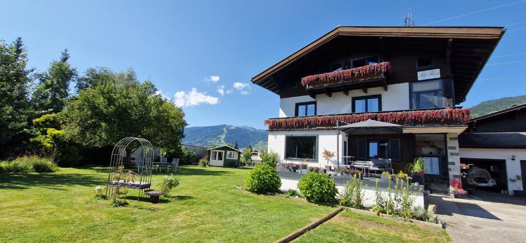 a large house with a grass yard in front of it at Alp Haus Grossglockner in Bruck an der Großglocknerstraße