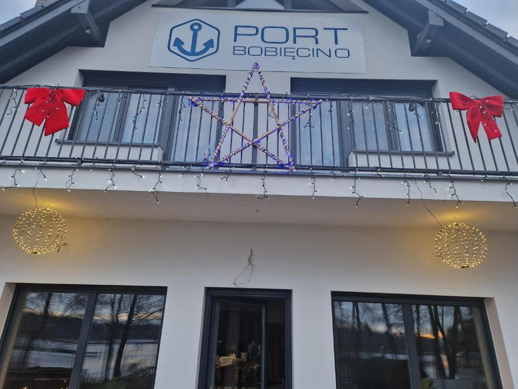 a white building with a balcony with a port aquarium sign at Port Bobięcino in Bobięcino