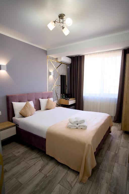 a bedroom with a large bed with two towels on it at Hotel Paris & SPA in Chişinău
