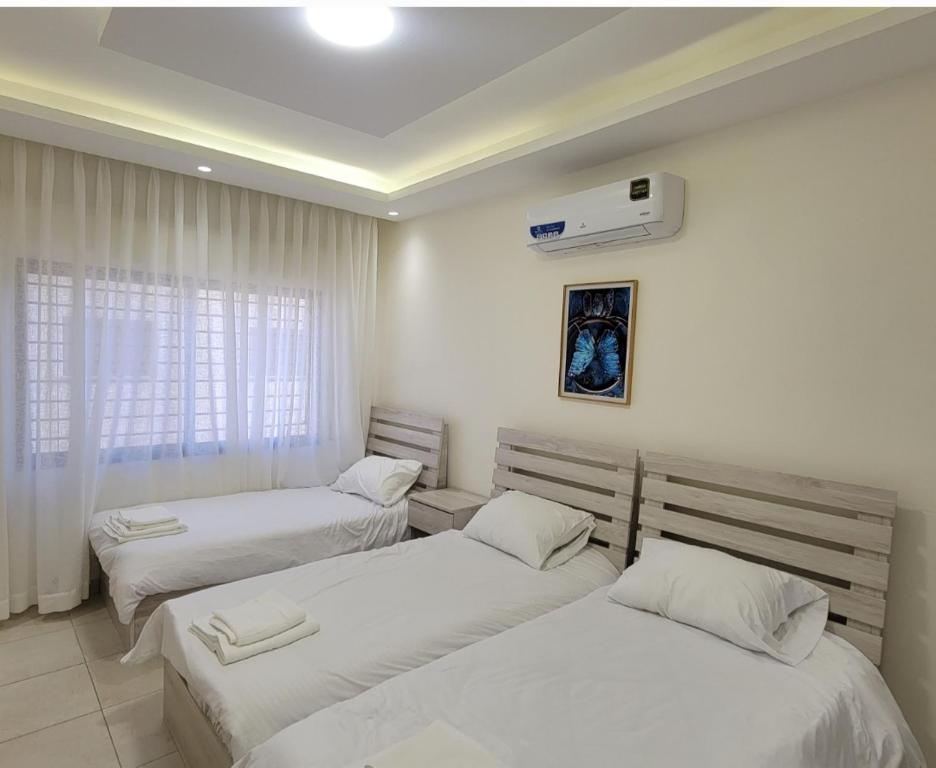 a room with two beds and a air conditioner at #302 brand new two large bedrooms in Rujm ash Sharāʼirah