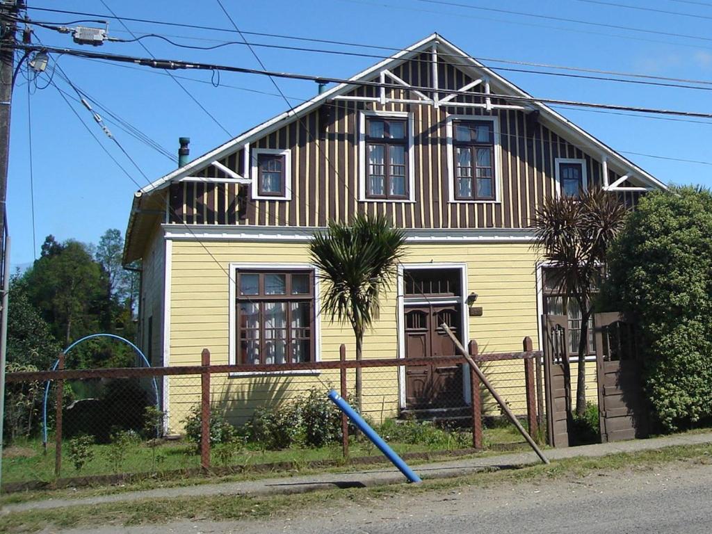 una casa amarilla con una valla delante de ella en La Casona del Buen dormir en Valdivia
