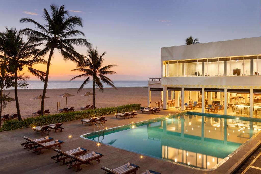 a building with a swimming pool next to the beach at Jetwing Sea in Negombo