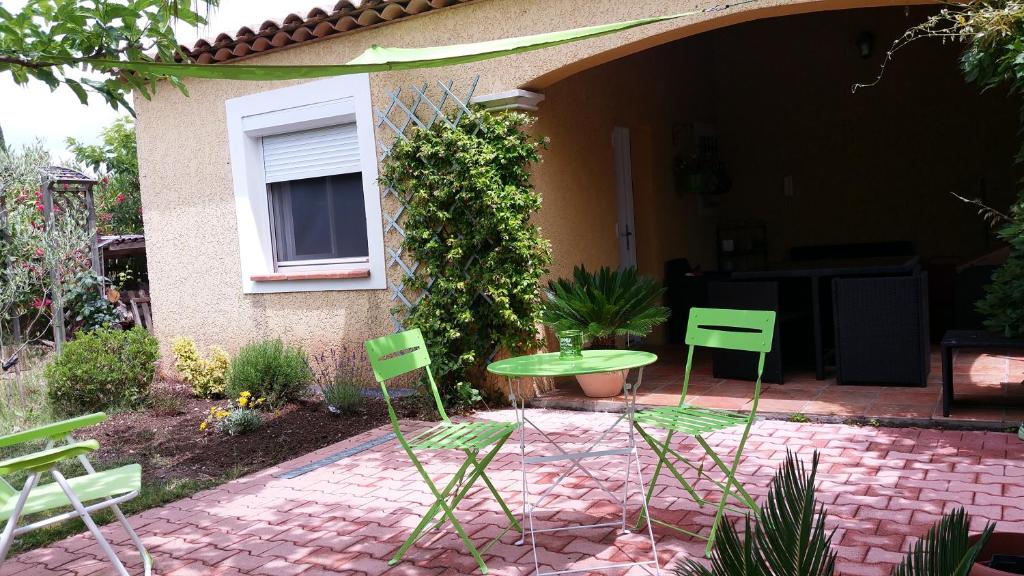 um pátio com cadeiras verdes e uma mesa em frente a uma casa em Petit studio au calme em La Crau