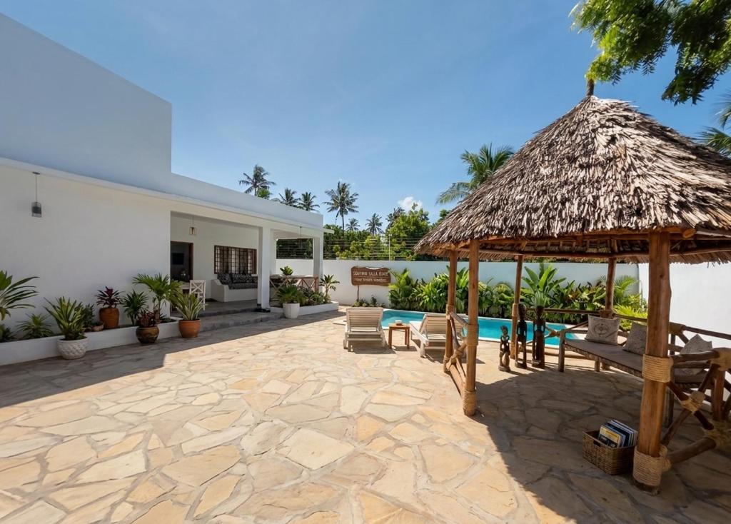 an outdoor patio with a thatched roof and a swimming pool at Daystar Villa in Watamu