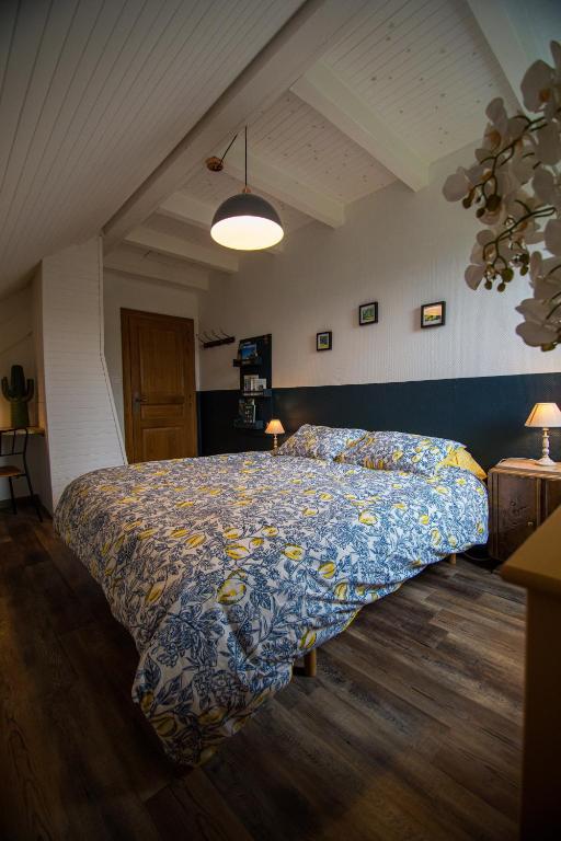 a bedroom with a bed with a blue and yellow bedspread at Le nid du Curtil - Chambre d'hôtes in Rougegoutte