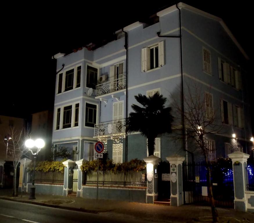 un edificio blanco con una palmera delante en B&B Elisir, en Albenga