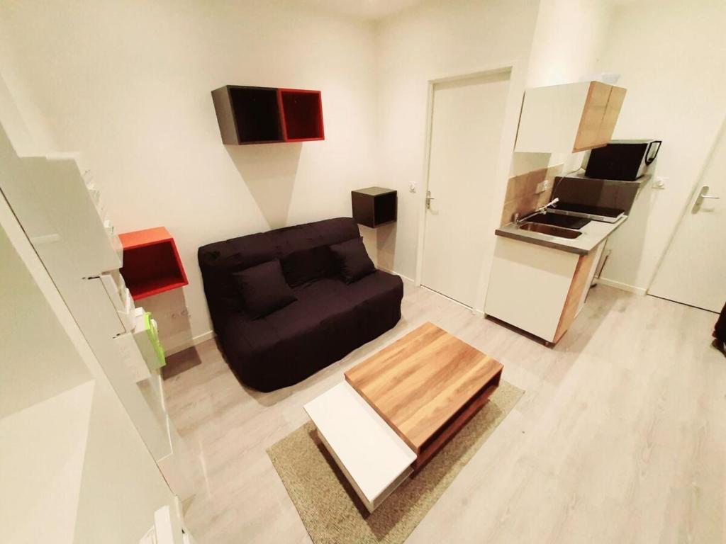 a living room with a black couch and a kitchen at Studio 2personnes entrée autonome in La Tronche