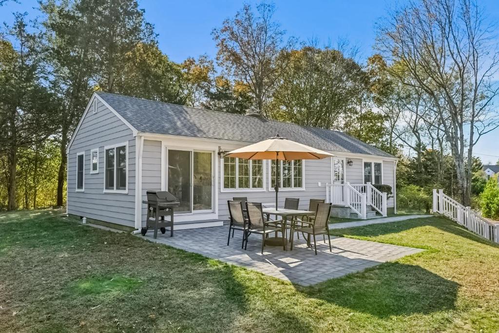 a small white cottage with a table and chairs at Steps to Beach + Sunset Views! East Marion Home in East Marion