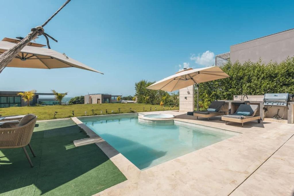 a swimming pool with two chairs and an umbrella at Bright villa w pool & outdoor grill u303 in Barú