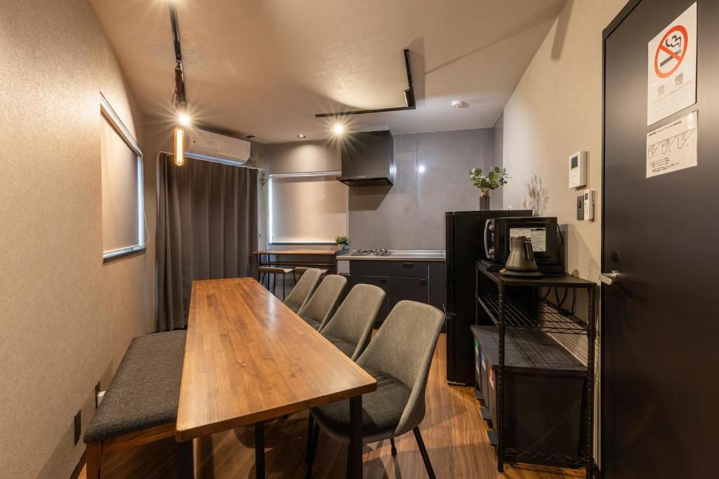 a room with a table and chairs and a kitchen at 翡翠名古屋本陣 in Nagoya