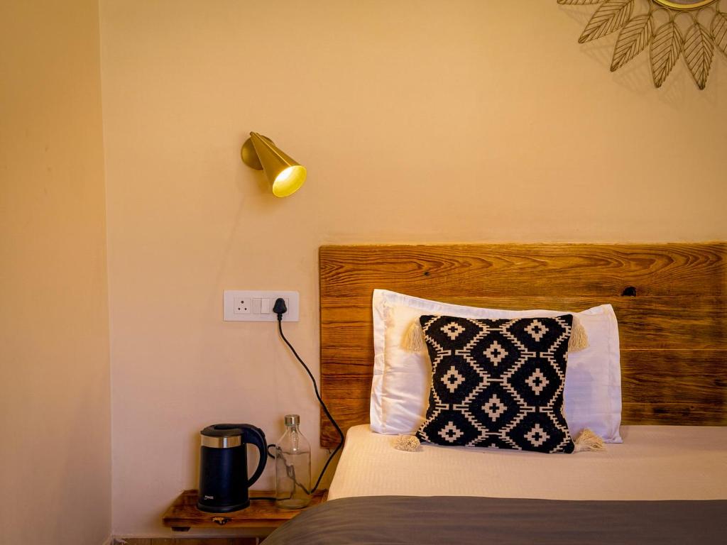 a bed with a black and white pillow and a lamp at Grham Hostel & Cafe Kasol, Katagla in Kasol