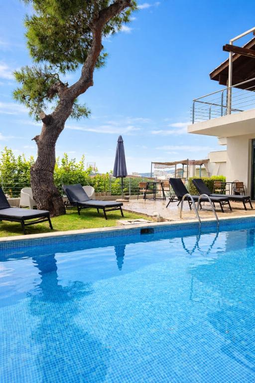 a pool with chairs and a tree next to a house at Ever Eden Residence by A&D Properties in Porto Rafti