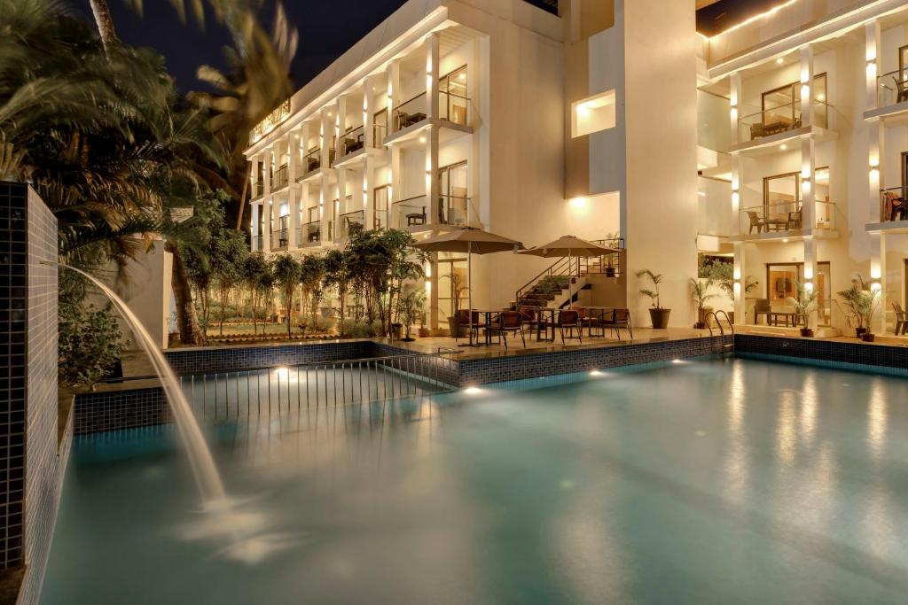 a swimming pool in front of a building at night at asar Upper House Morjim Beach by Orion Hotels in Morjim