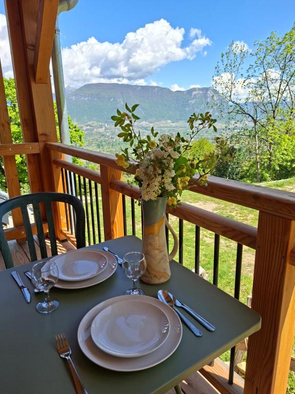 a table with plates and a vase of flowers on a porch at Chalet du Mont Granier in Apremont