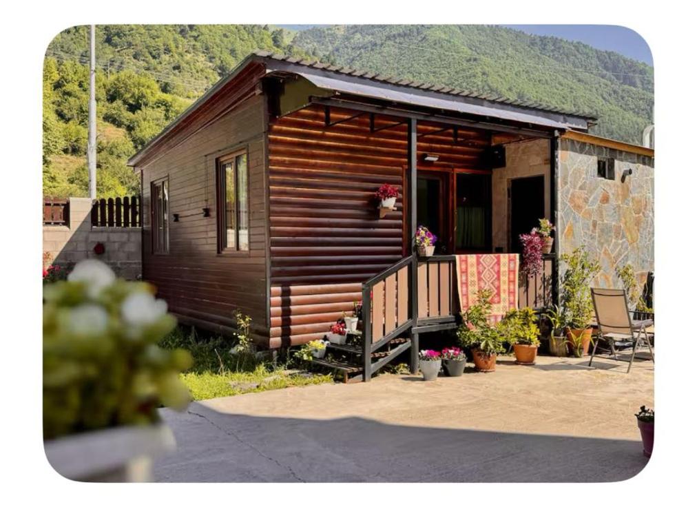 a small wooden cabin with a porch and a patio at Mestia Alpine Cottage in Mestia
