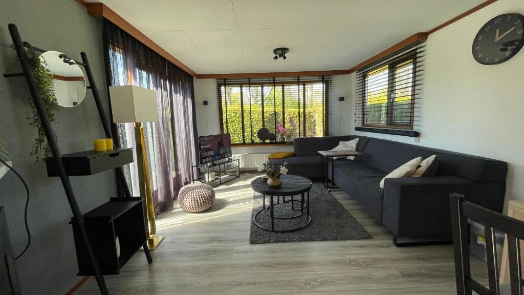 a living room with a couch and a table at Geniet van rust en privacy in onze gezellige chalet op familiecamping De Tien Heugten in Drenthe in Schoonloo