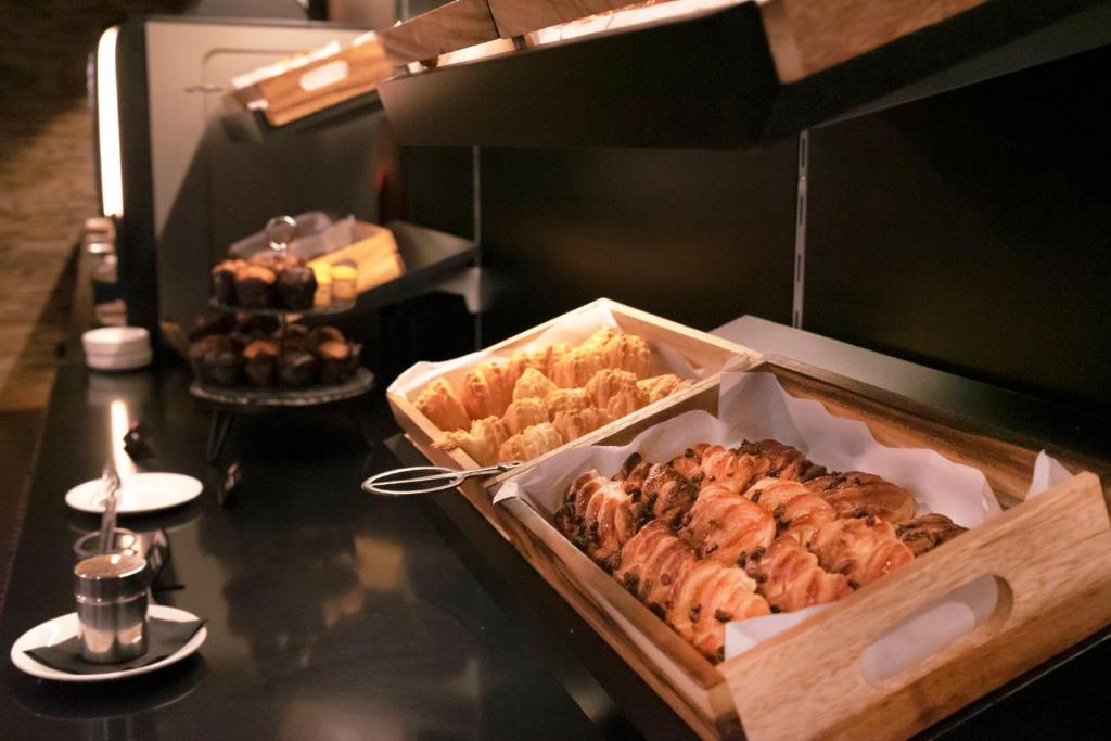 Pastries are arranged in wooden trays on a dark breakfast counter.