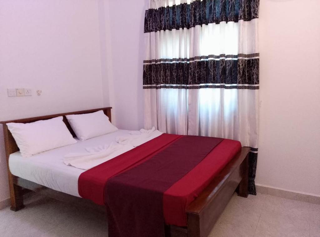 a bedroom with a bed with a red and black blanket at Ceylon Seaway Villa in Trincomalee
