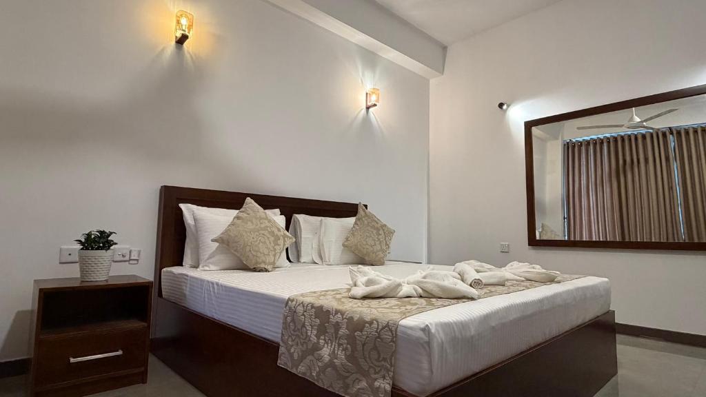 a bedroom with a large bed and a mirror at Solar Airport Hotel in Seeduwa