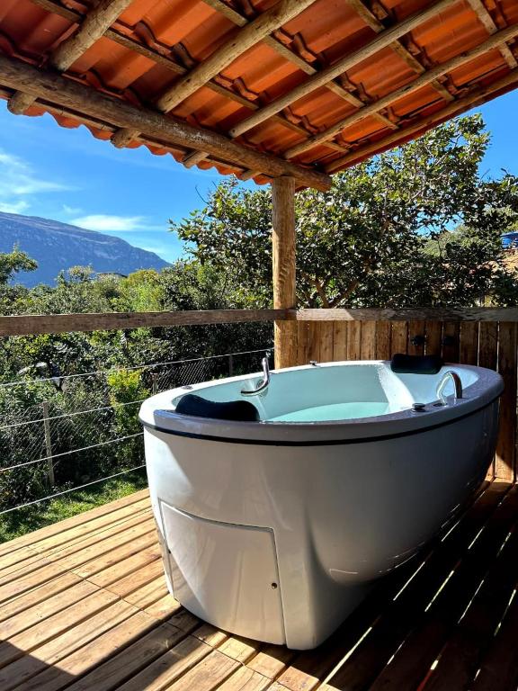 a bath tub sitting on a deck with a pergola at Chalé Aconchego da Lapinha Vista para Montanhas Piscina e Natureza in Santana do Riacho