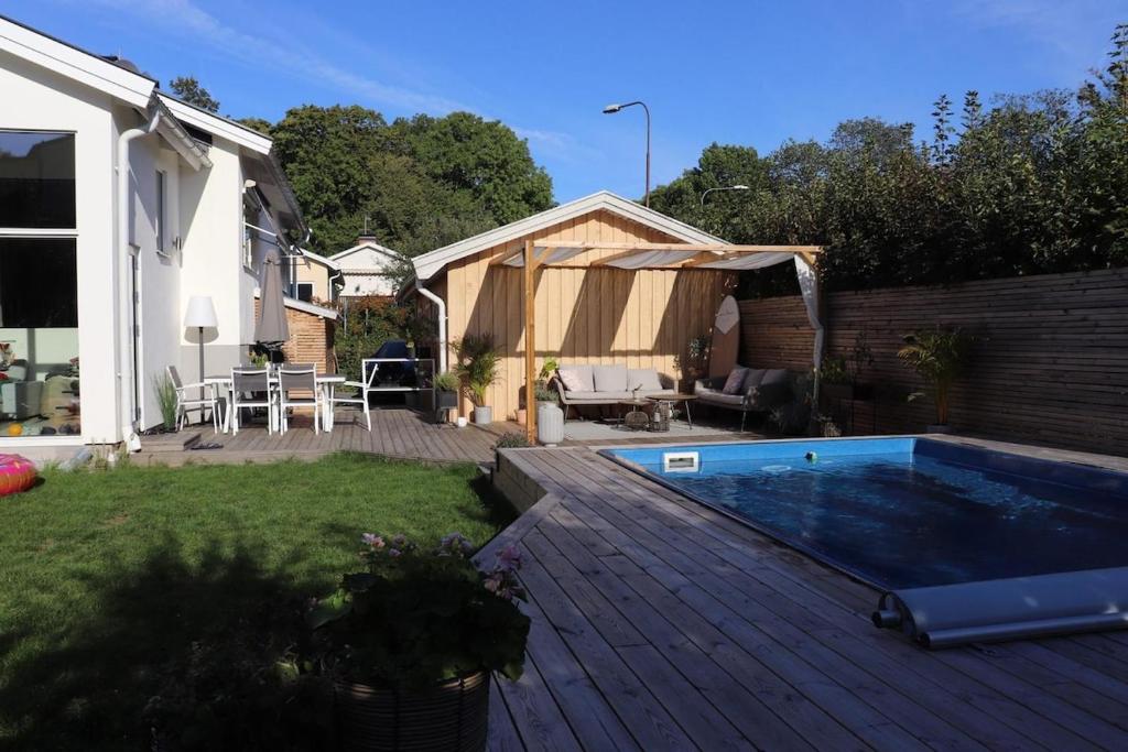 a backyard with a wooden deck and a swimming pool at Villa med Pool in Stockholm