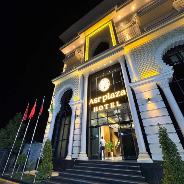 a man standing outside of a hotel at night at ASR Plaza in Jizzax