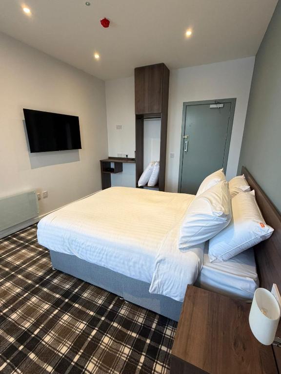 a hotel room with a bed and a flat screen tv at Claremont Hotel in Alloa