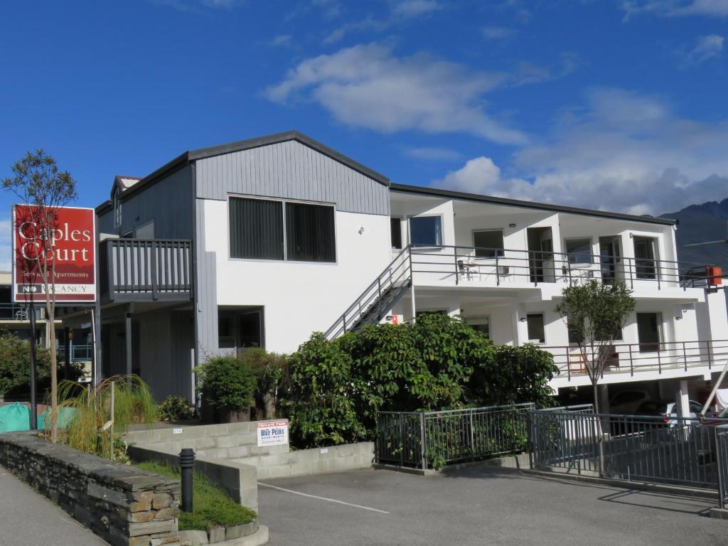 a white building with a sign in a parking lot at Caples Court Motel & Apartments in Queenstown