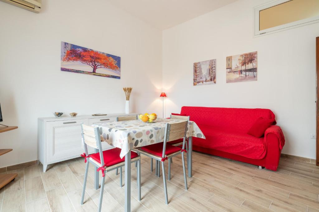 a living room with a table and a red couch at Appartamento il Decimomiglio in Decimomannu