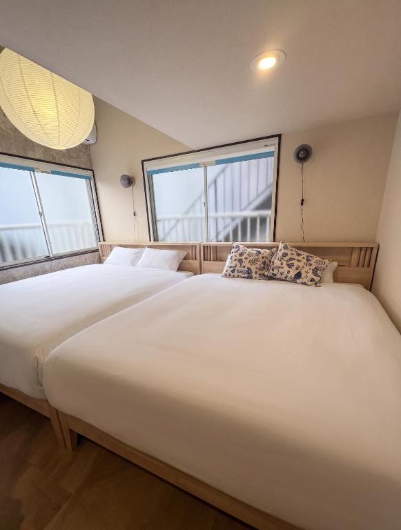 a large white bed in a room with two windows at Shinjuku Topshot Hotel in Tokyo