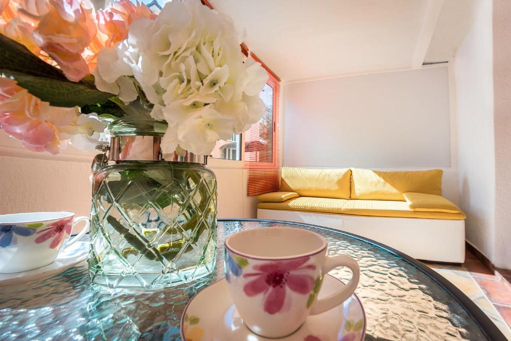 a glass table with a vase with flowers and a cup at Mango Apartment Petrovac in Petrovac na Moru