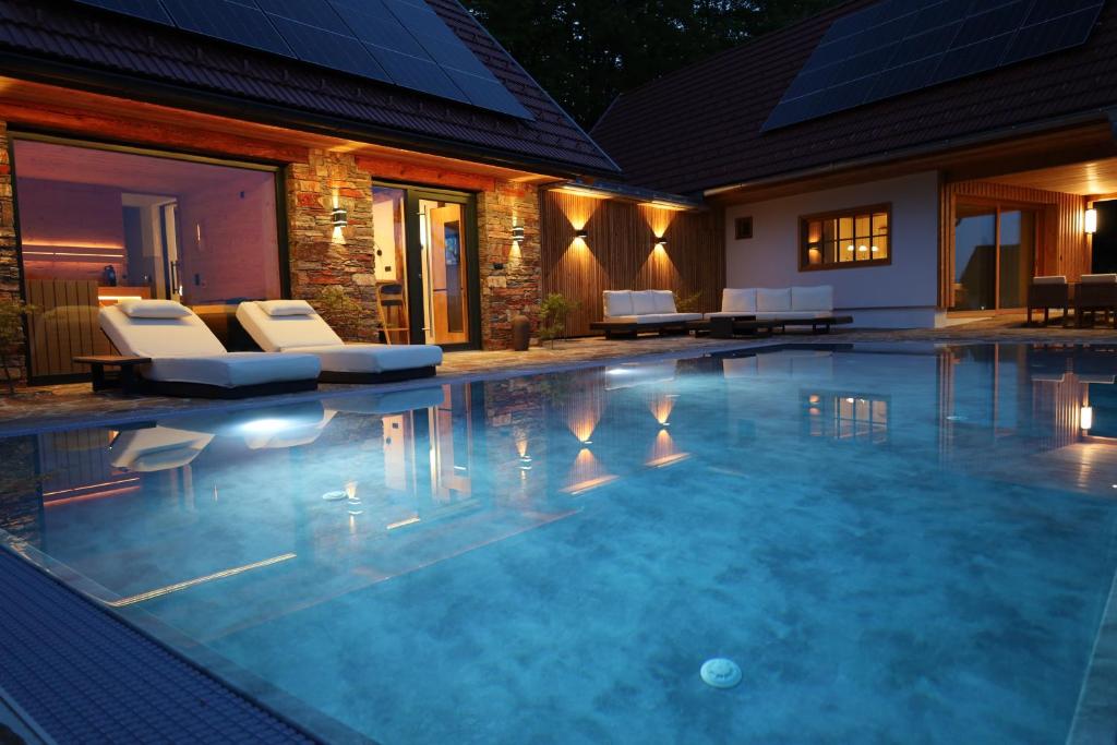 a swimming pool with chairs and a house at Der Distelfalter in Oberhaag