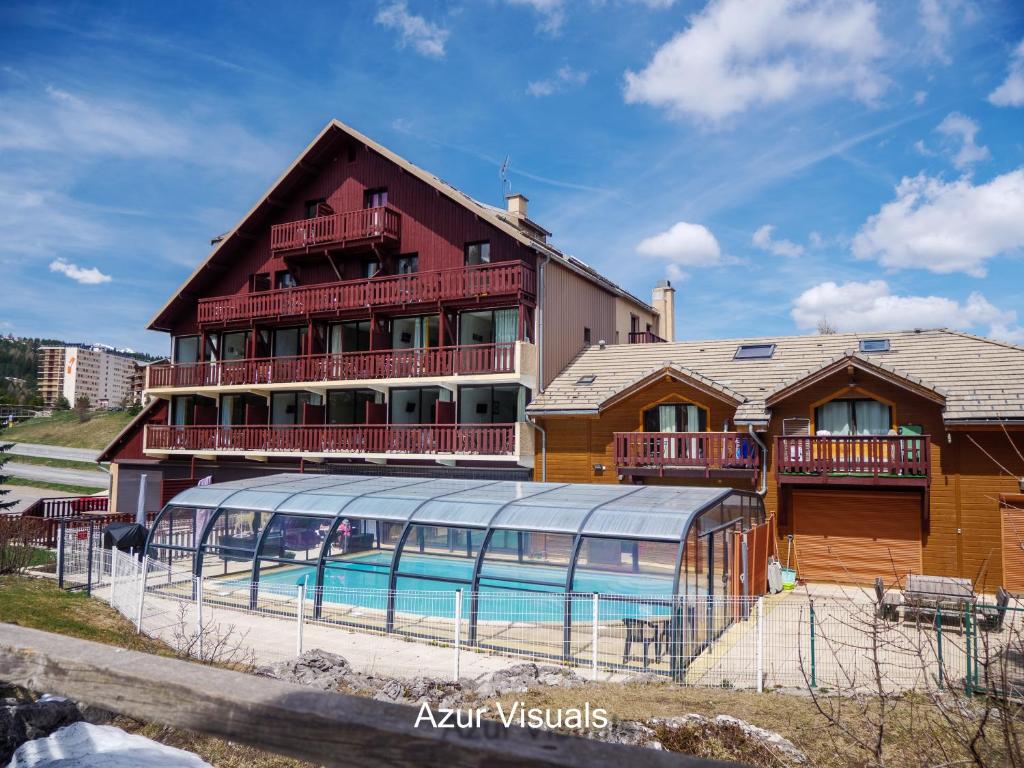 a building with a swimming pool in front of it at Hôtel Chalets Margot in Le Dévoluy