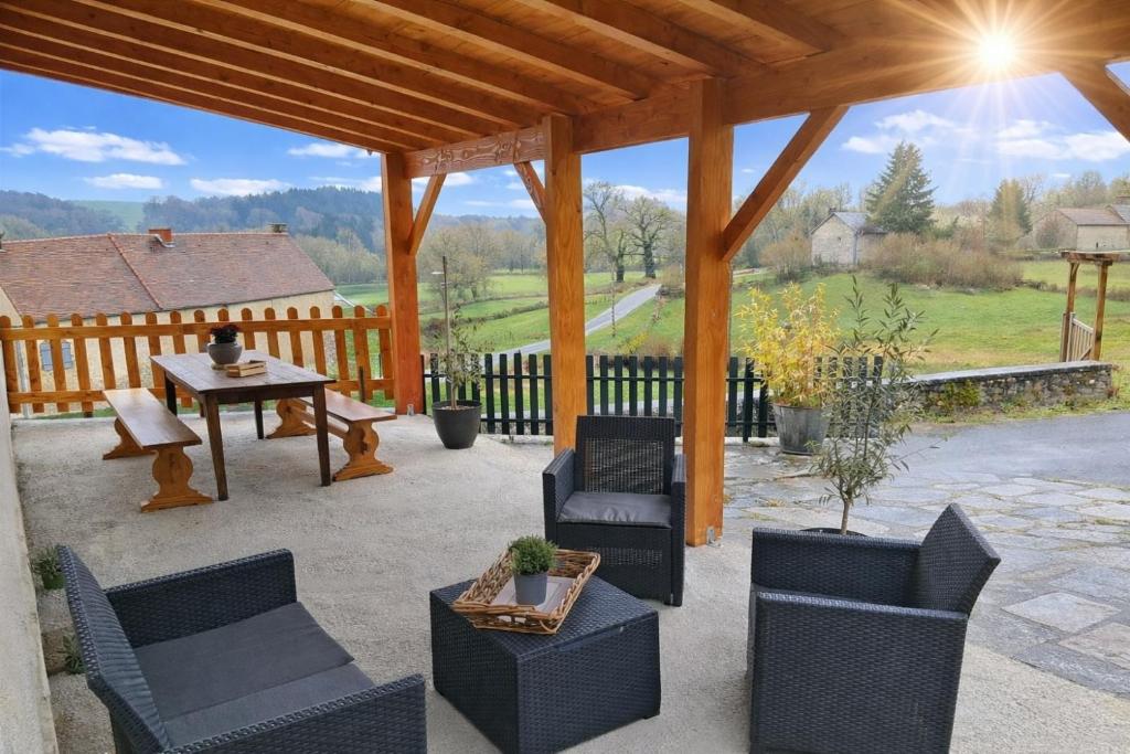 a patio with chairs and a table and a wooden pergola at Gîte La Belle du Clocher in Saint-Pardoux-dʼArnet