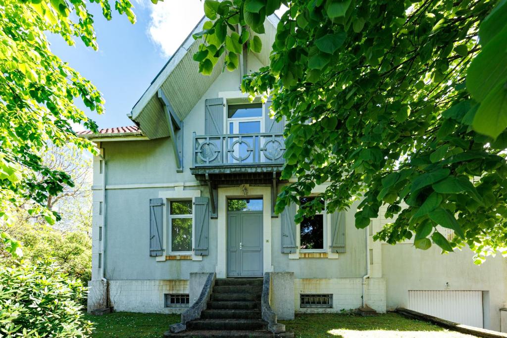 a white house with a blue door and stairs at Villa Yantet - Conciergerieland in Soustons