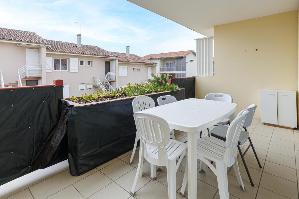 a white table and chairs on a balcony at Aux Gourbets - Conciergerieland in Vieux-Boucau-les-Bains