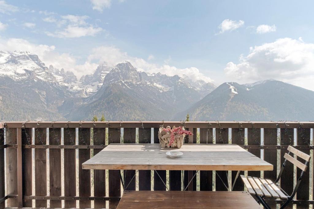 a table on a deck with a view of mountains at Relax At The Mountain in Madonna di Campiglio