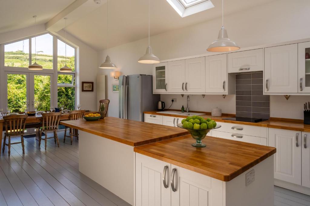 a kitchen with white cabinets and a table with a bowl of fruit at Chuggs Orchard in Croyde