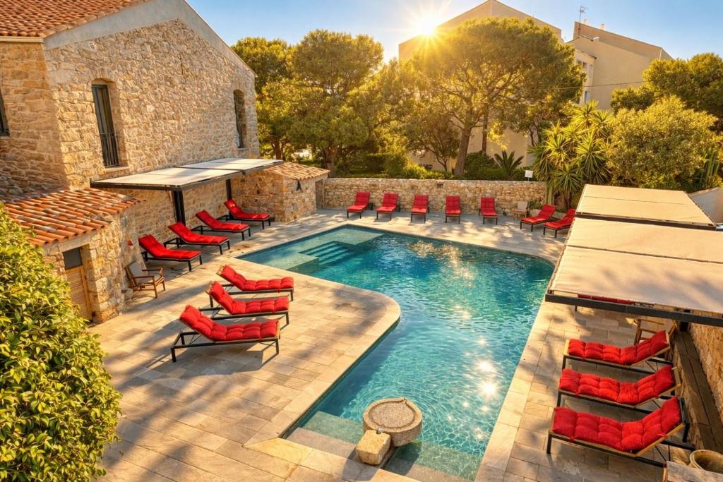 an outdoor pool with red chairs and a swimming pool at Hôtel Casa Rossa & Spa in LʼÎle-Rousse