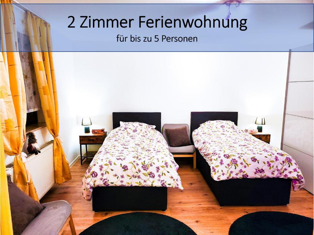two beds in a room with two chairs and a bedskirts at My FeWo in Germersheim