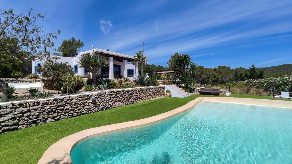 a house with a swimming pool next to a stone wall at Villa Radi by Eivillas in Santa Gertrudis de Fruitera